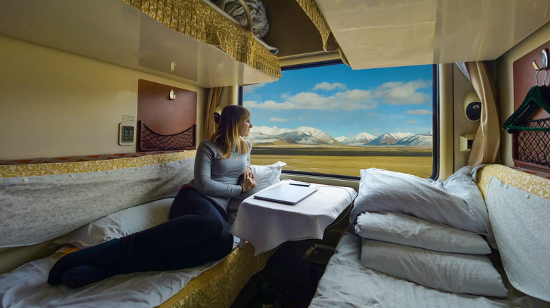 Woman sitting on a bed on a sleeper train