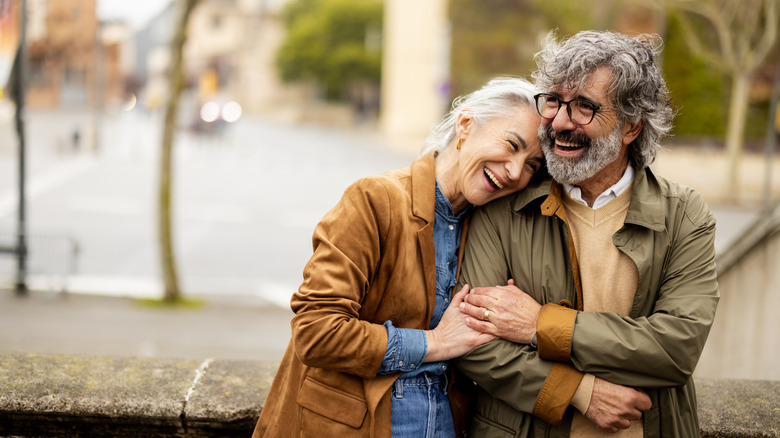 A happy retired couple laughing and hugging each other.