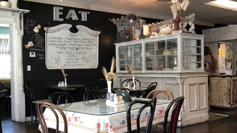 A table inside the Spring Creek Tea Room in Ozark, Missouri, with a rustic white cabinet and an "Eat" sign in the background.