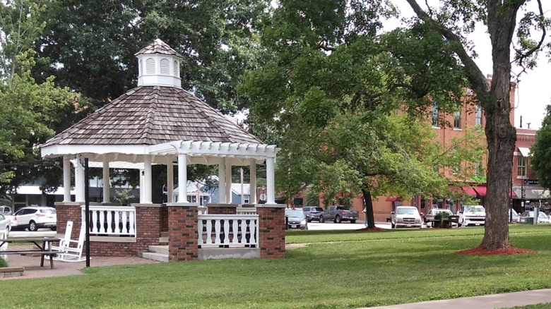 A brick gazebo with white pillars and gray shingles on the lawn at Ozark Square in Ozark, Missouri.