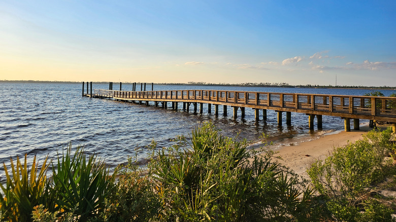 A long wooden jetty and dock off a sandy North Bay shoreline at Lynn Haven Bayou Park & Preserve.