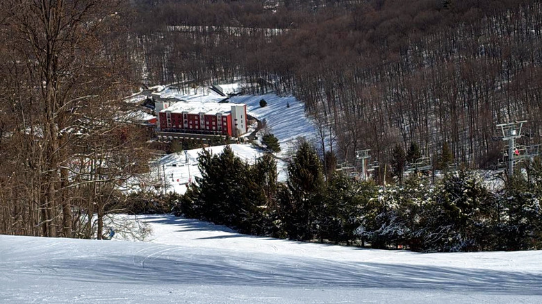 Snowy ski slopes and wintry trees overlooking the Bear Creek Mountain Resort building in Macungie Pennslyvania