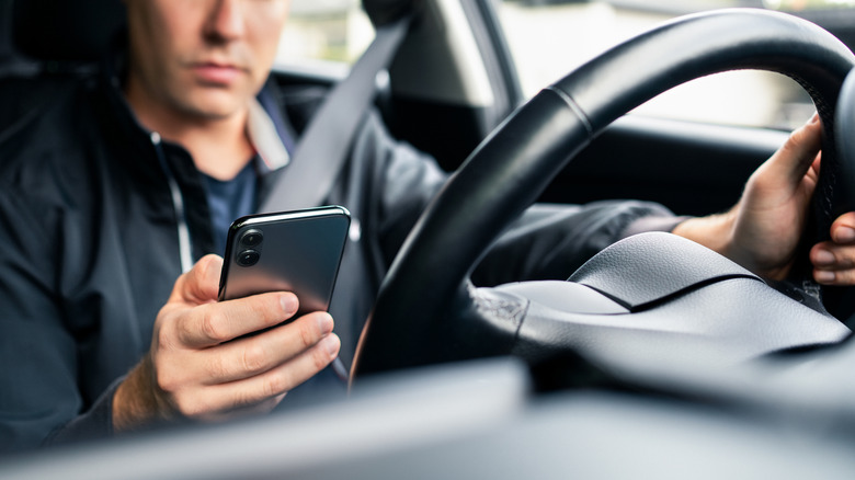 A driver checks his phone while operating a car