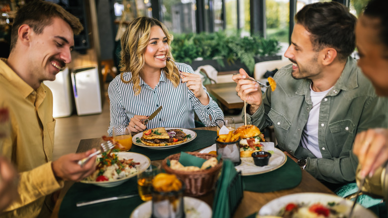 A group of people smile and enjoy a meal at table