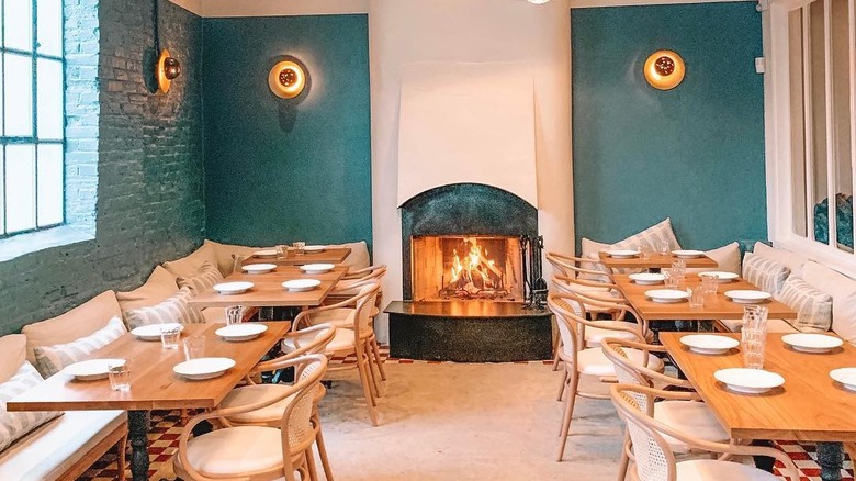 The interior at Suraya restaurant in Philadelphia, with wooden tables, teal walls, and a fireplace