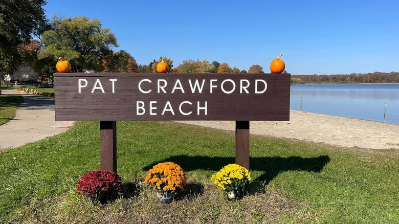 Sign for Pat Crawford Beach with sand and lake in the background