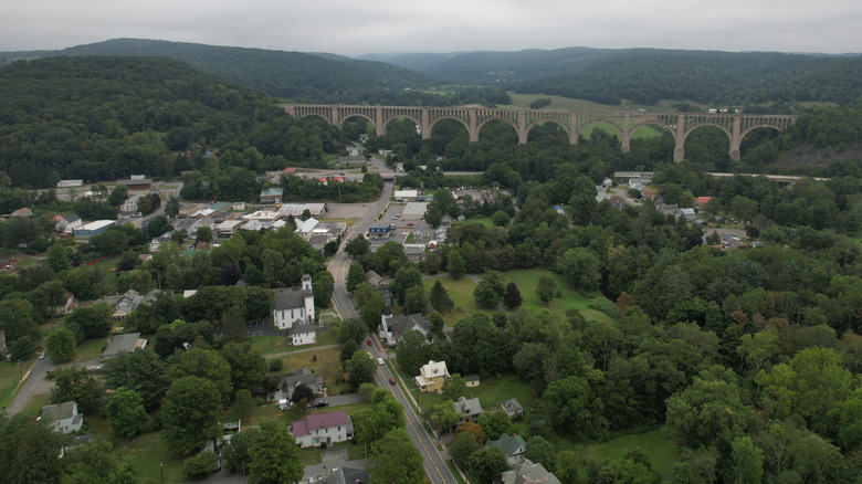 Aerial view of Nicholson, Pennsylvania and the Tunkhannock Viaduct, surrounded by tree-covered hills under a cloudy sky
