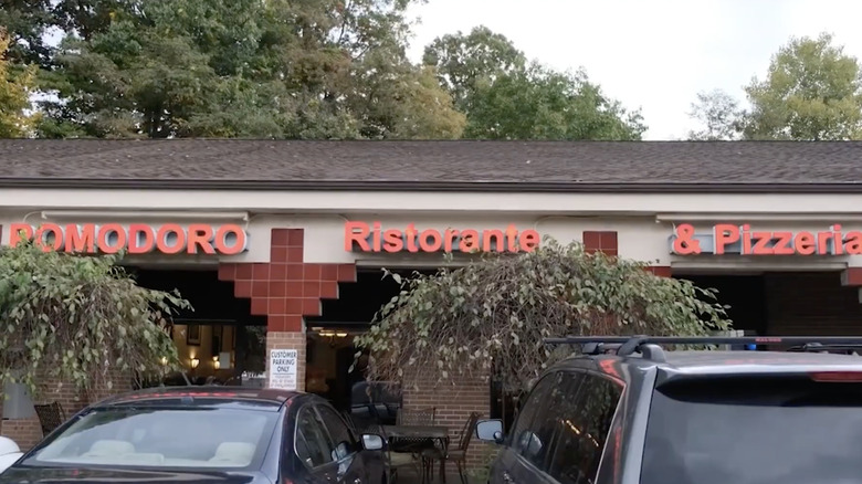Red letters on a brick building with parked cars in front