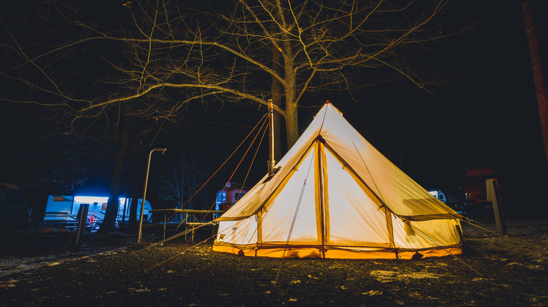 A tent set up at night in Promised Land State Park with caravans in the background.