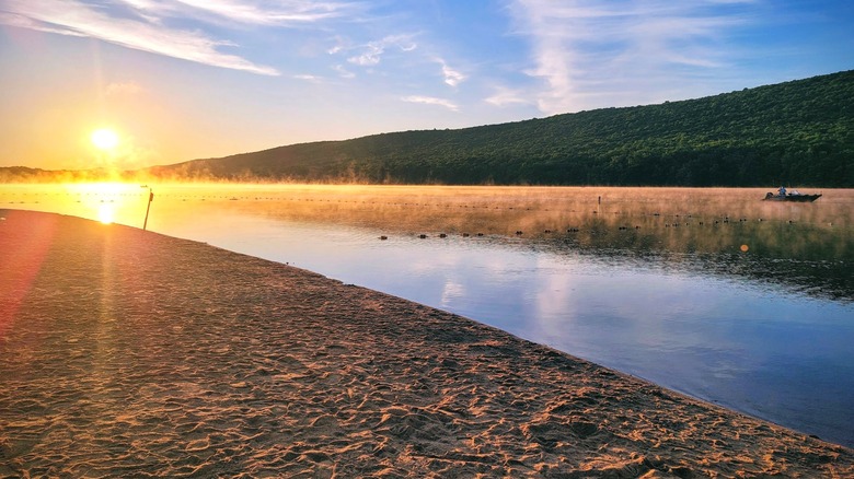Sunrise and thin morning mist over Mauch Chunk Lake as seem from the sandy beach.
