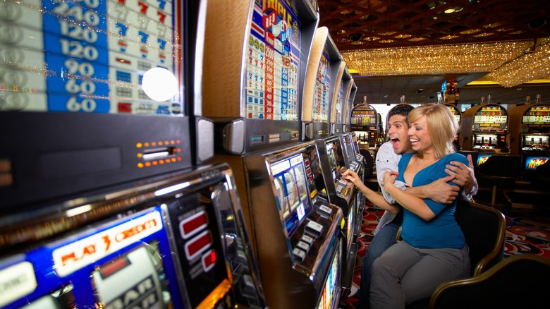 An excited couple play the slots on a casino gaming floor