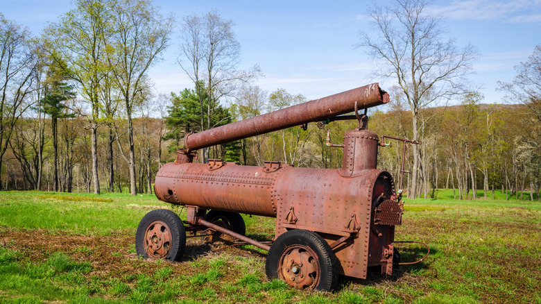 Rusted oil-drilling equipment on green grass at Historic Pithole City