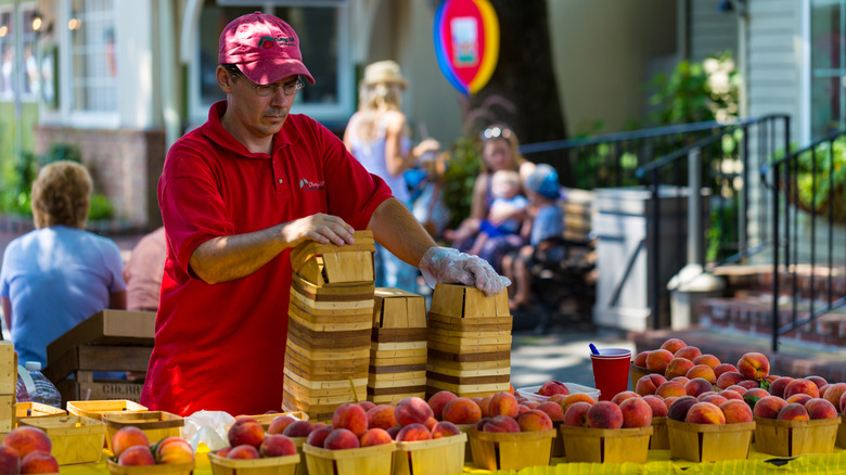 A vendor sells baskets of fresh peaches at Kitchen Kettle Village.