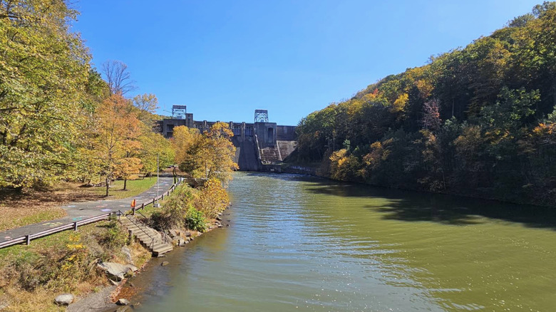 Mahoning Creek Lake and dam on a sunny day, surrounded by fall foliage.