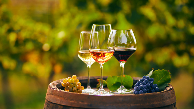 Wine glasses sitting on a barrel with grapes