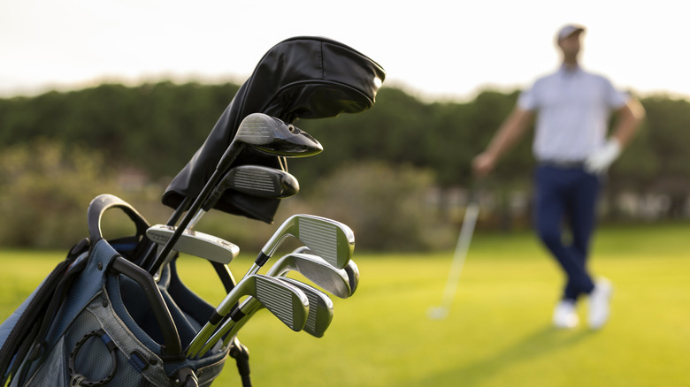 A golfer poses near his bag and clubs
