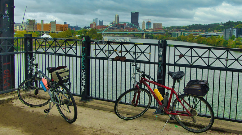Two cycles parked along a railing overlooking the river and bridge in Pittsburgh