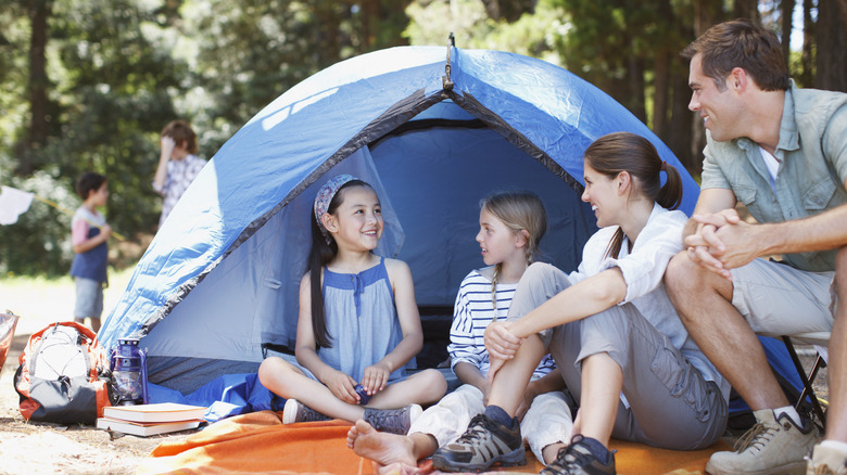 Family with kids in tent on wooded site