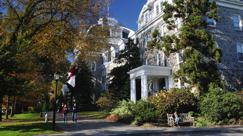 Campus buildings in Swarthmore, Pennsylvania, with two people walking down a tree-lined sidewalk and someone sitting on a bench in the foreground