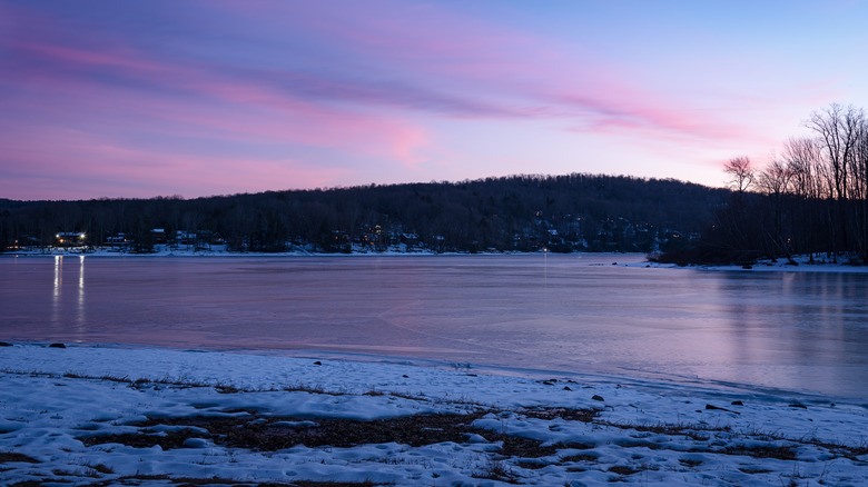 Lake Ariel in Pennsylvania during the early evening with snow on the shore and houses in the background