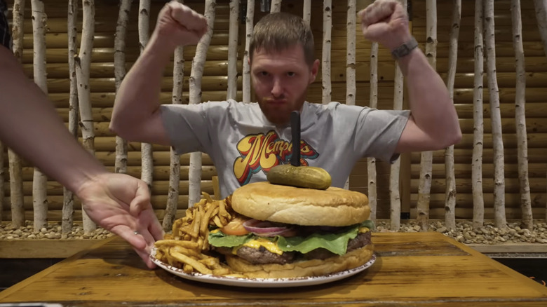 A man pumps his fists in front of the massive Kookamonga Burger