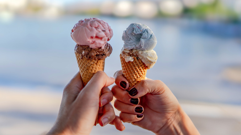 two travelers holding ice cream cones with different colored ice cream inside