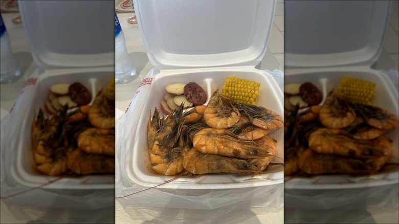 to-go container with cob corn and large whole shrimp
