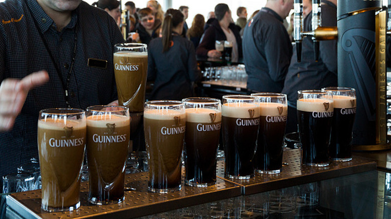 A line of glasses in the midst of a pour of Guinness