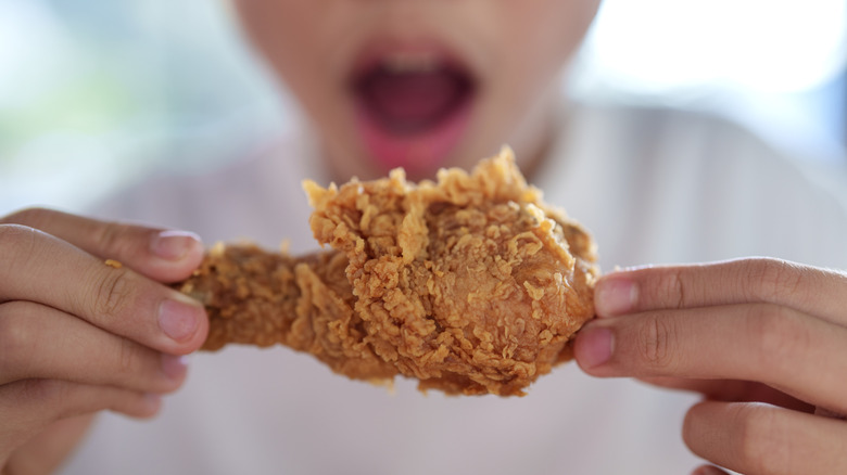 Close up of a child eating fried chicken