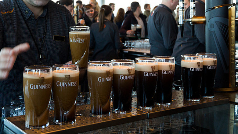 A line of glasses in the midst of a pour of Guinness
