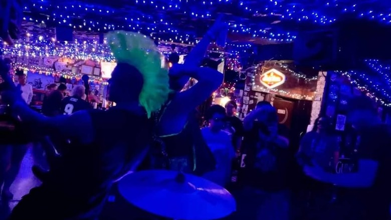 guy with green mohawk in crowded dark bar with blacklights
