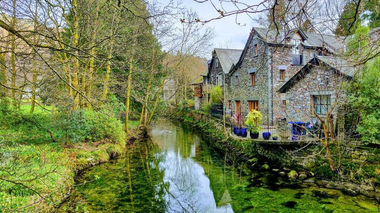 Stone buildings and forests of Grasmere lining the Rothay river