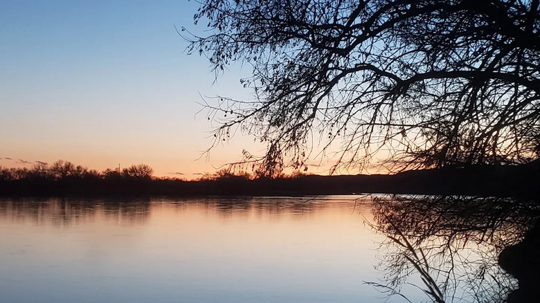 Sunset over a tree-lined river from Pirogue Island State Park