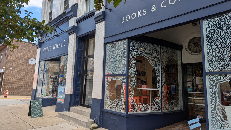 Storefront of White Whale Bookstore, a white brick building with blue accents and large windows decorated with white squiggles