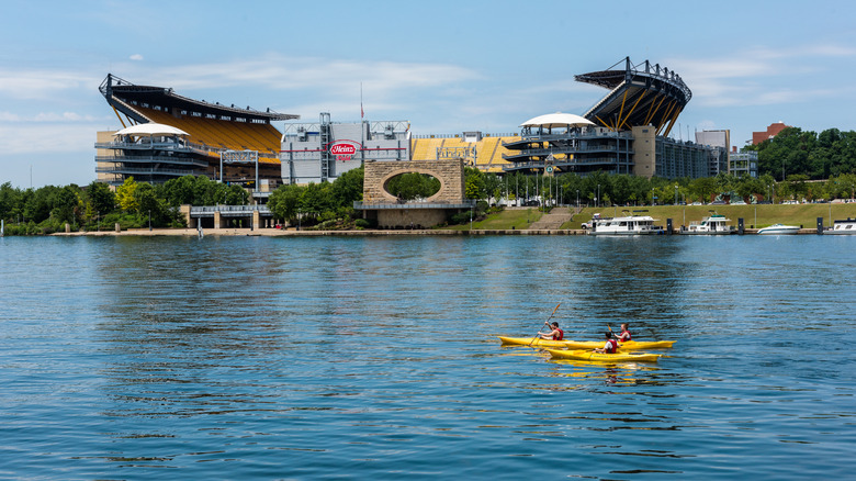 Three people kayaking in the Allegheny River in front of Heinz Field, home of the Pittsburgh Steelers