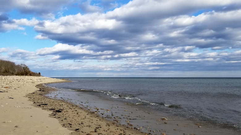 Dense, silver stratus clouds hover low above a calm, gray sea on a winter day at Plymouth County's Center Hill Preserve in Massachusetts
