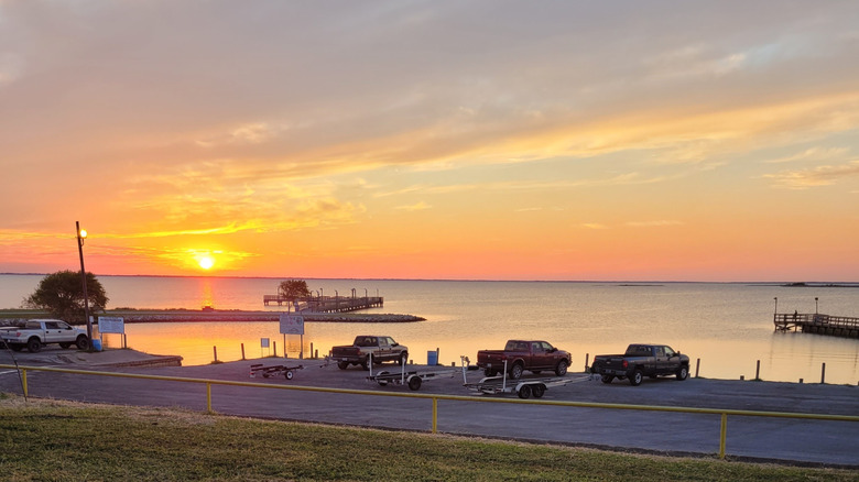 Waterfront Park in Point Comfort with the bay, fishing piers, and trucks with boat trailers parked in the parking area in view.