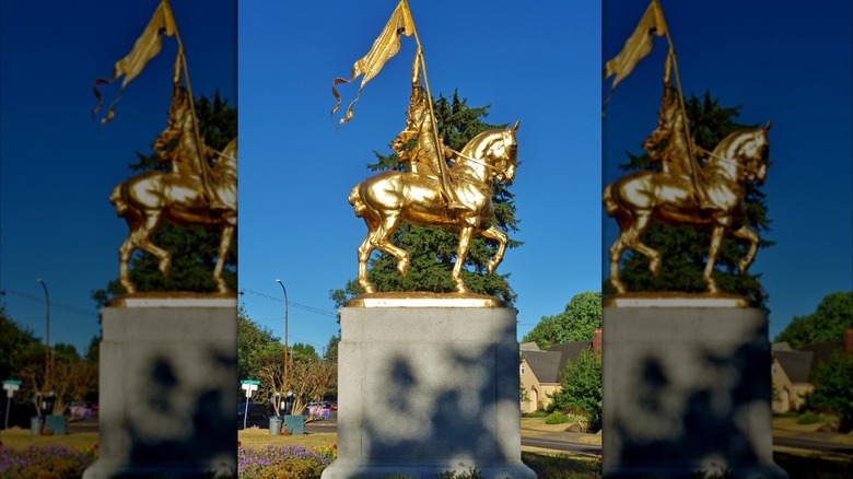 Joan of Arc statue in Coe Circle with homes in the background, under a blue sky