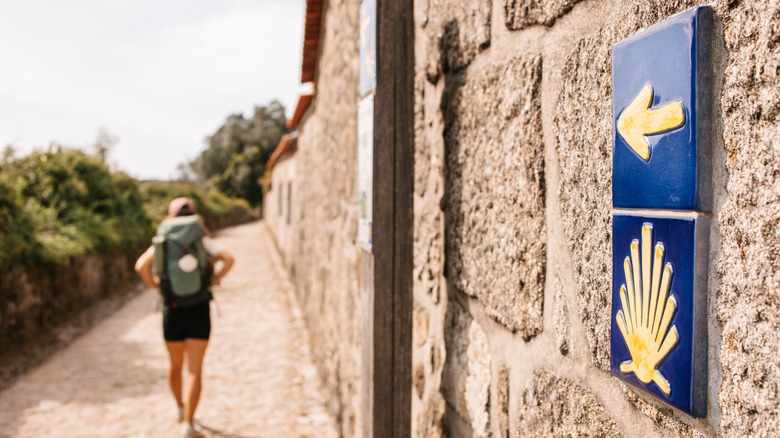 Hiker walking on the Camino de Santiago with a sign pointing in the direction