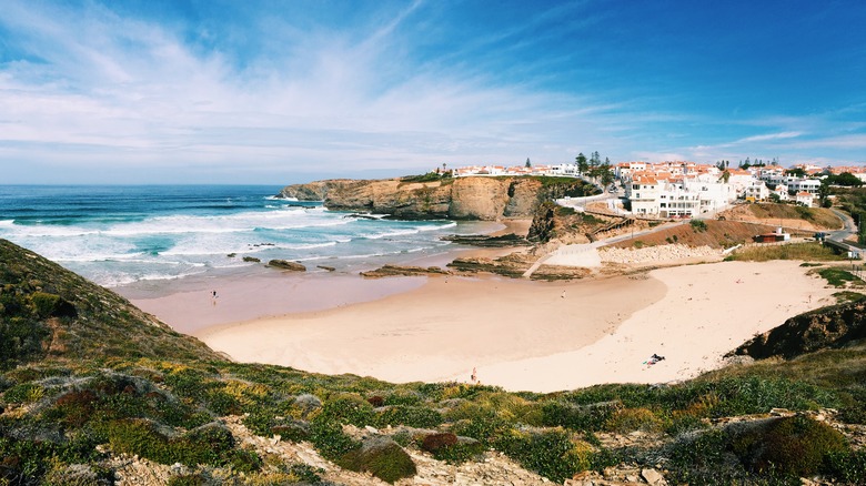 White houses with red tile roofs on cliffs overlooking golden sand beach