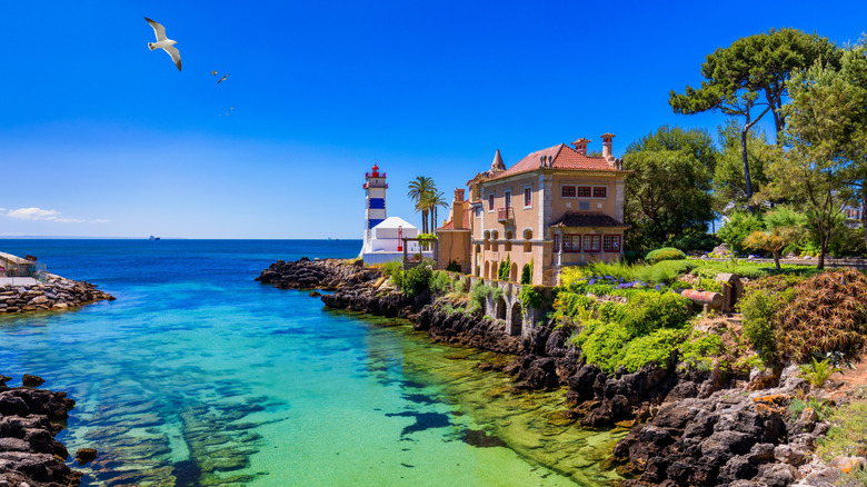 Turquoise cove overlooking a historic palace and lighthouse in Cascais, Portugal