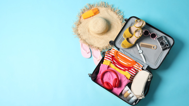 An overhead view of a suitcase with high heels, clothes, and accessories