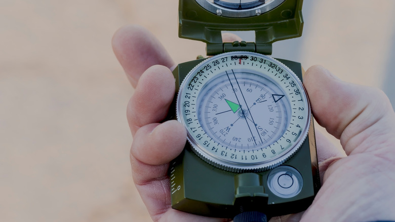 A hand holding a military-grade compass