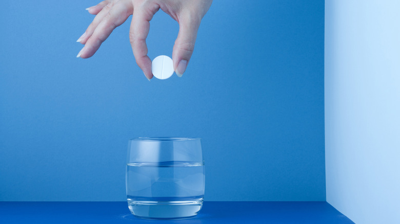 Person dropping purifying pill in glass of water