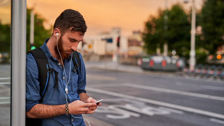 A man waits for the bus on an empty street