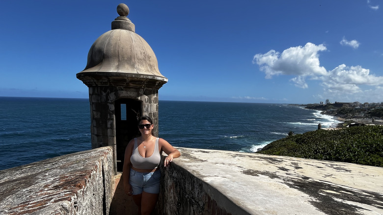 Woman standing in front of a garitas with ocean and coastal views at El Morro Castle in Old San Juan