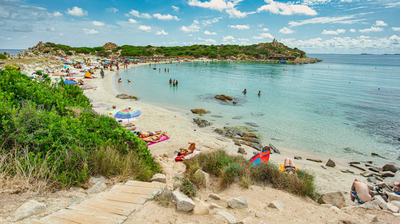Umbrellas and beachgoers at Punta Molentis beach in Villasimius, Sardinia