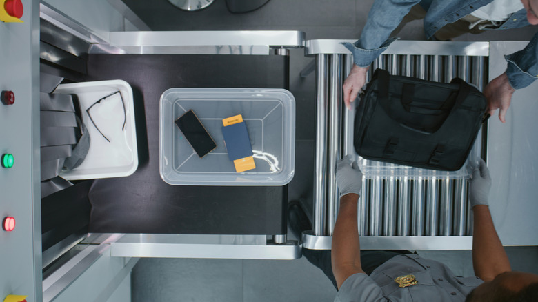A passenger sends their belongings through a TSA screening