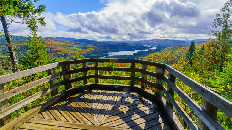 A wooden overlook platform with mountain views and a lake.