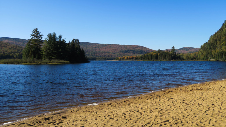 Sandy shore at La Crémaillère with the blue water of Lake Monroe in Canada's Mont-Tremblant National Park